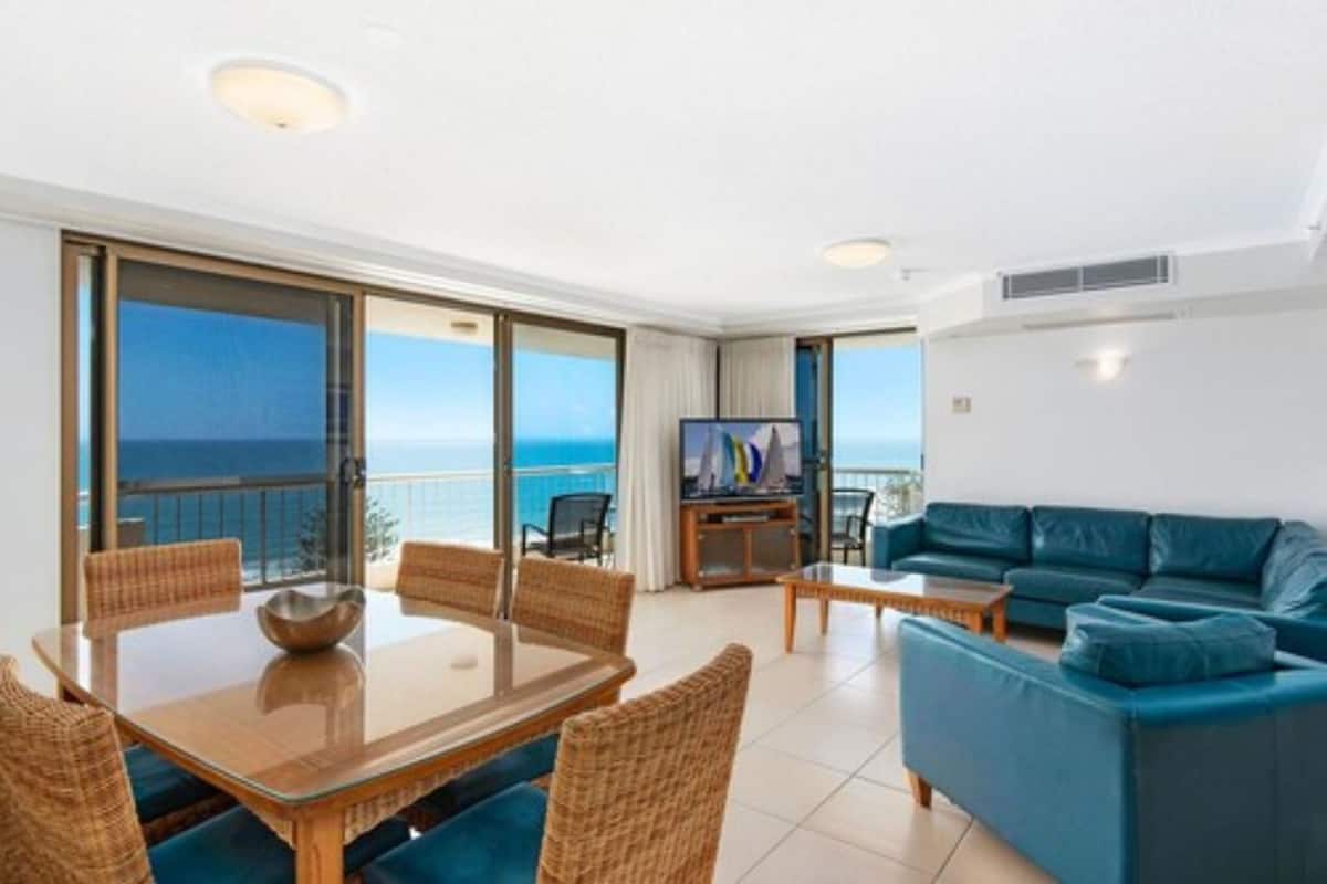 A modern living room with a balcony, a dining area, and a TV.