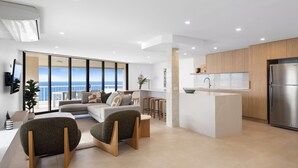 A modern living room with a sofa, two armchairs, a coffee table, and a view of the ocean. - Coolum Caprice (Coolum Beach)