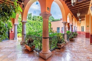 A covered courtyard with arches, tiled flooring, and potted plants. - Antigua Capilla B&B (San Miguel de Allende)