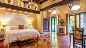 Un dormitorio amplio con una cama grande, un banco, una chimenea y un comedor con sillas.