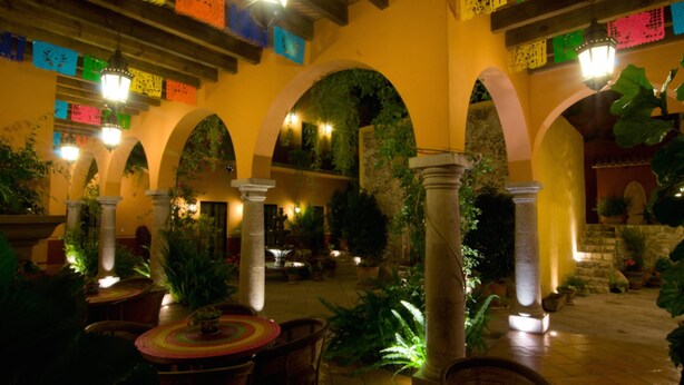 Un patio interior con arcos, columnas y plantas en macetas.