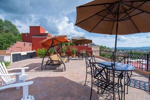 An outdoor patio with seating, umbrellas, and a view of the landscape. - Antigua Capilla B&B (San Miguel de Allende)