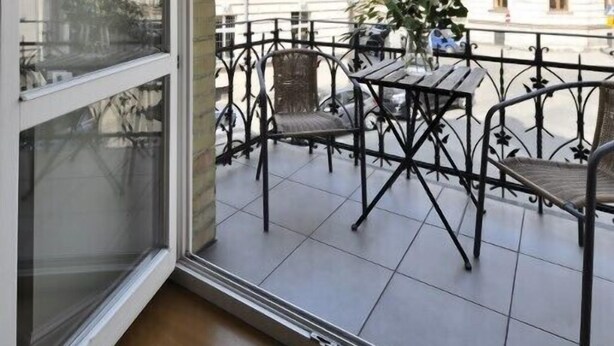 A balcony with a view of classical buildings, a table, and chairs. - Crystal Suites Old Town (Kraków)
