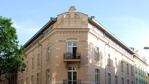 A multi-story building with a classic architectural style, featuring a central entrance with a door and a small balcony above. - Crystal Suites Old Town (Kraków)