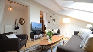 A modern living room with a sofa, coffee table, and TV. - Crystal Suites Old Town (Kraków)