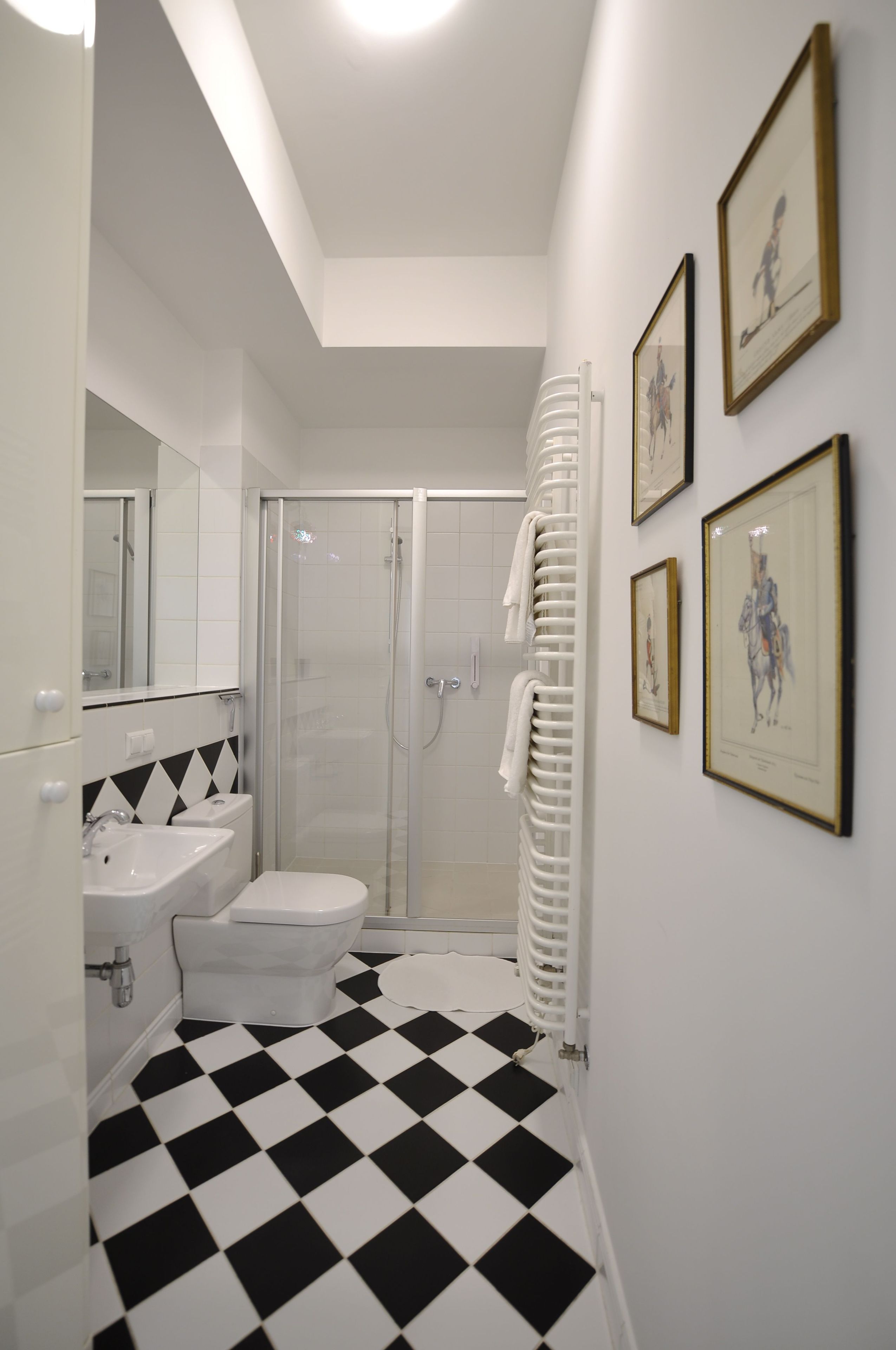 A bathroom with a black and white checkered floor, a white sink, a toilet, and a glass shower enclosure.