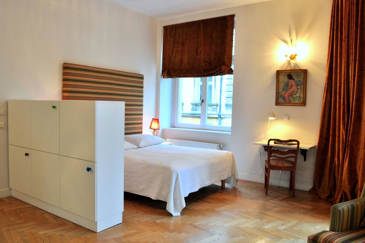 Une chambre à coucher comprenant un lit, un bureau, une chaise, un radiateur et une armoire.