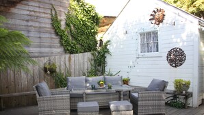 A patio with wicker furniture, a table, and potted plants. - Seagull Inn (Mendocino)