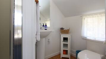 Un baño pequeño y blanco con lavamanos, espejo y ventana.