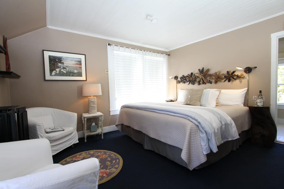 A bedroom with a bed, a chair, a lamp, and a picture on the wall.