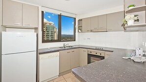 A modern kitchen with a dishwasher, oven, and a window offering a city view.