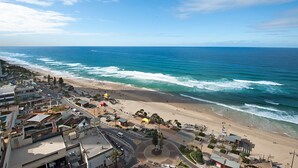 A coastal cityscape with a beach, buildings, and a roundabout.