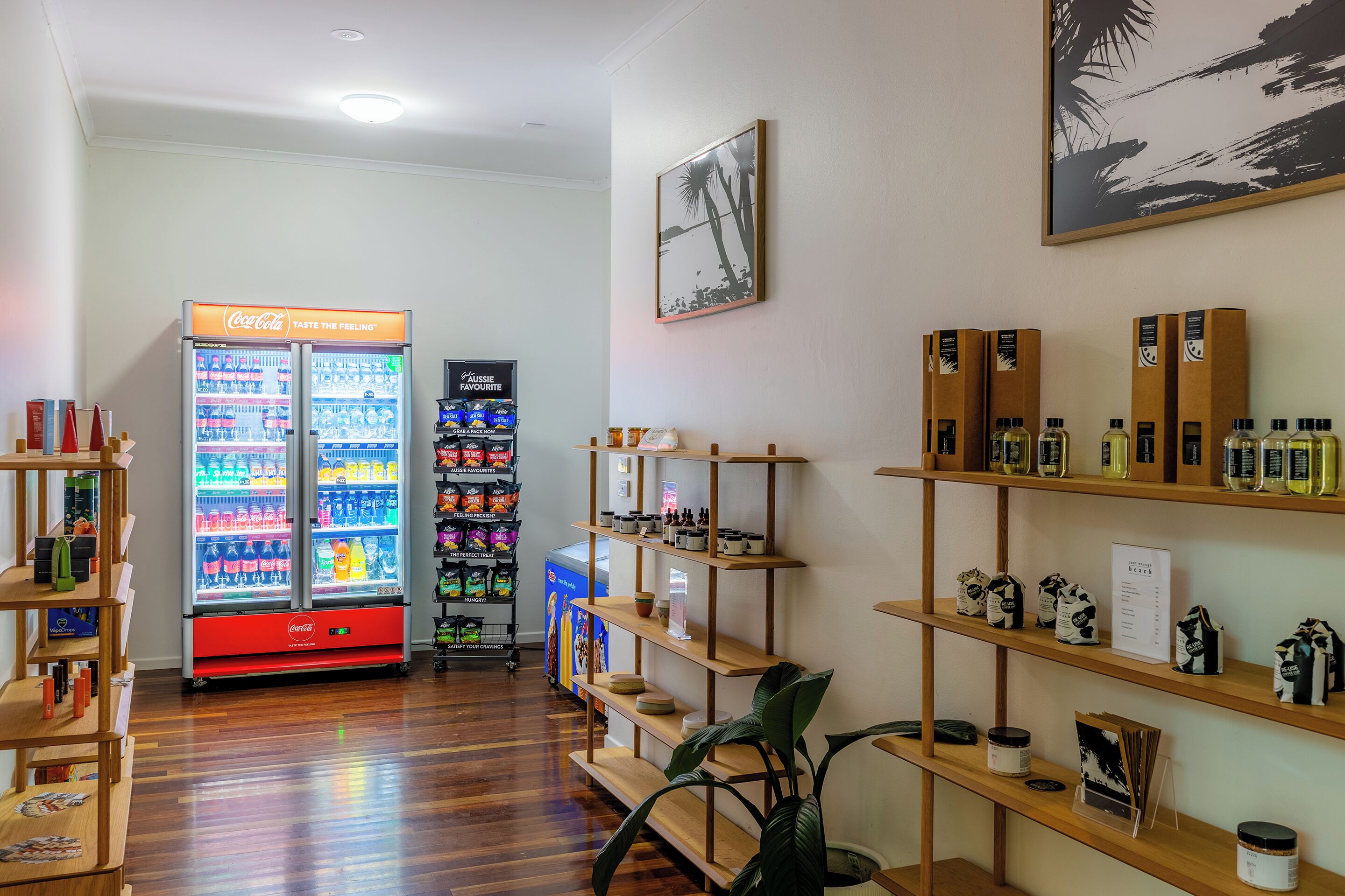 A clean, well-organized room with wooden shelves displaying various items, a Coca-Cola refrigerator, and a vending machine.