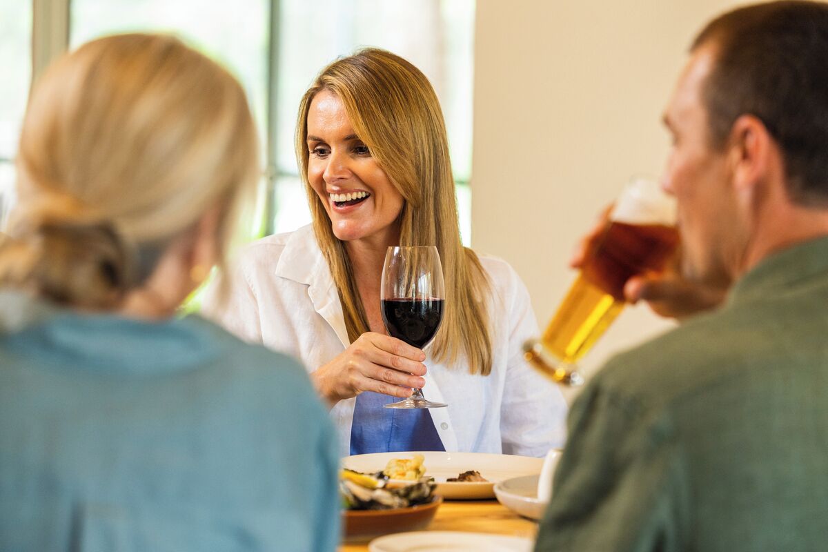 A dining table with people seated around it, holding wine glasses.