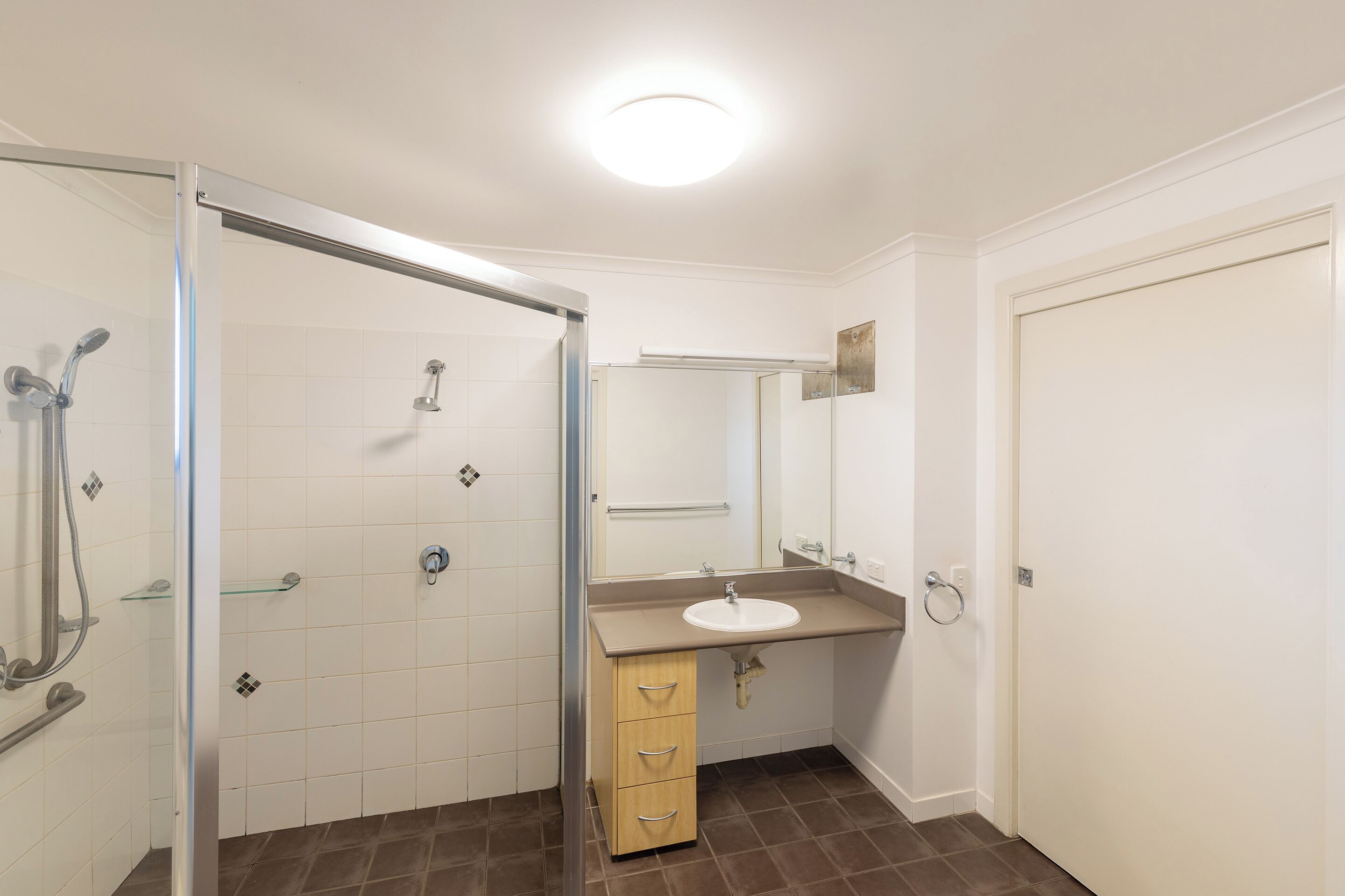 A bathroom with a shower, sink, and mirror.