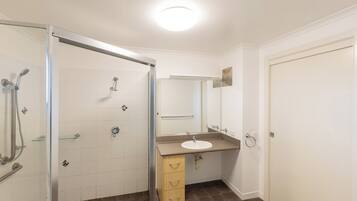 A bathroom with a shower, sink, and mirror.