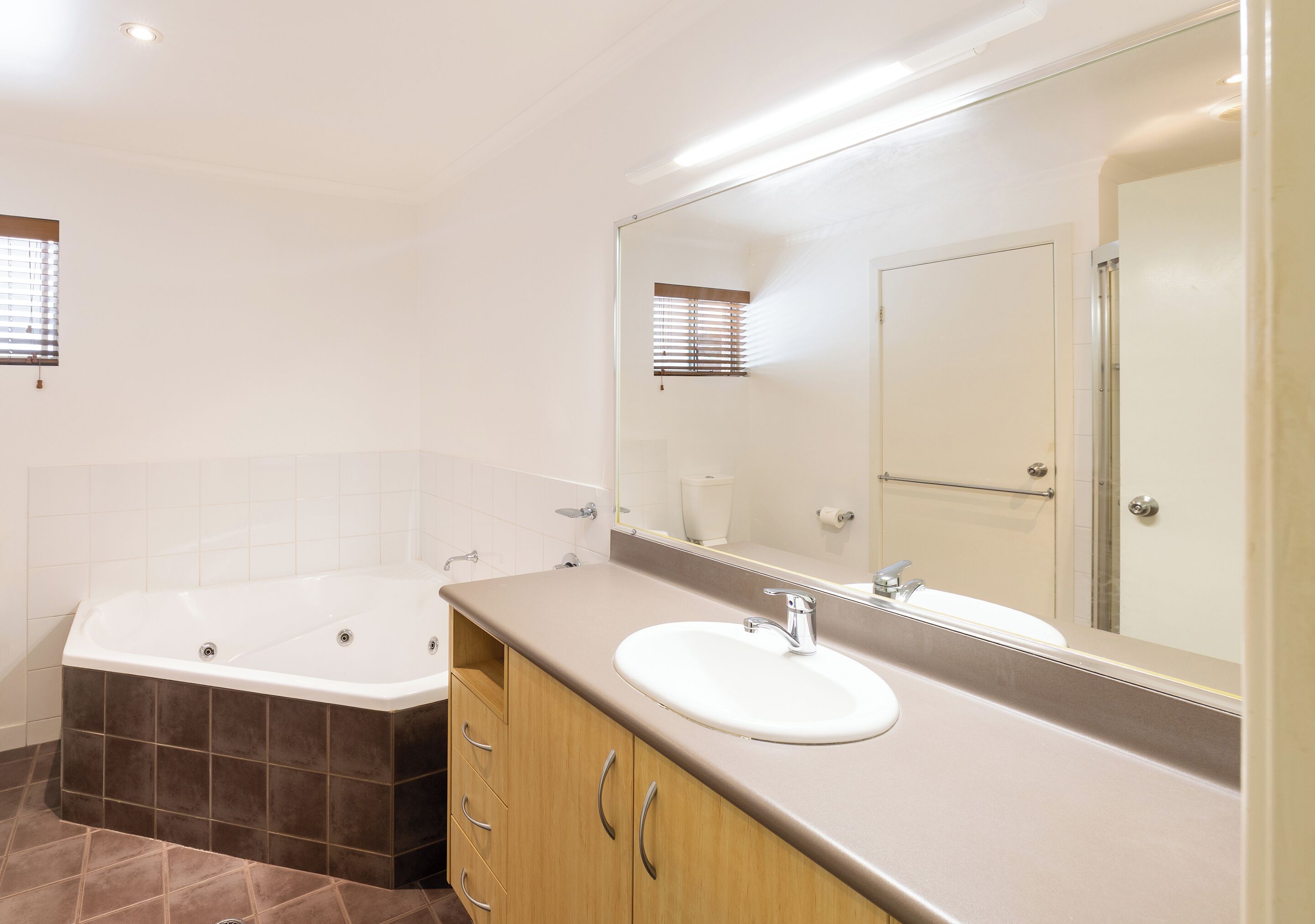 A bathroom with a bathtub, sink, vanity, and a large mirror.