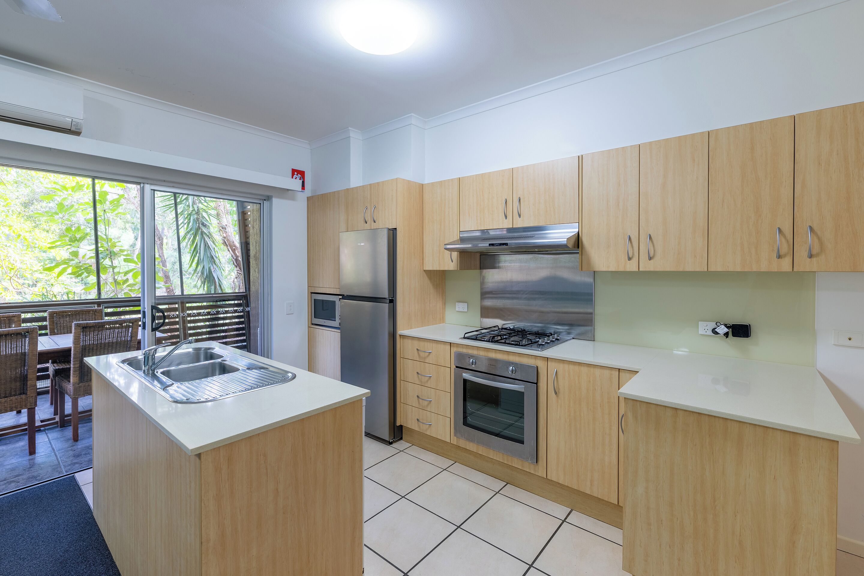 Een moderne keuken met een centraal eiland, roestvrijstalen apparatuur en houten kastjes.