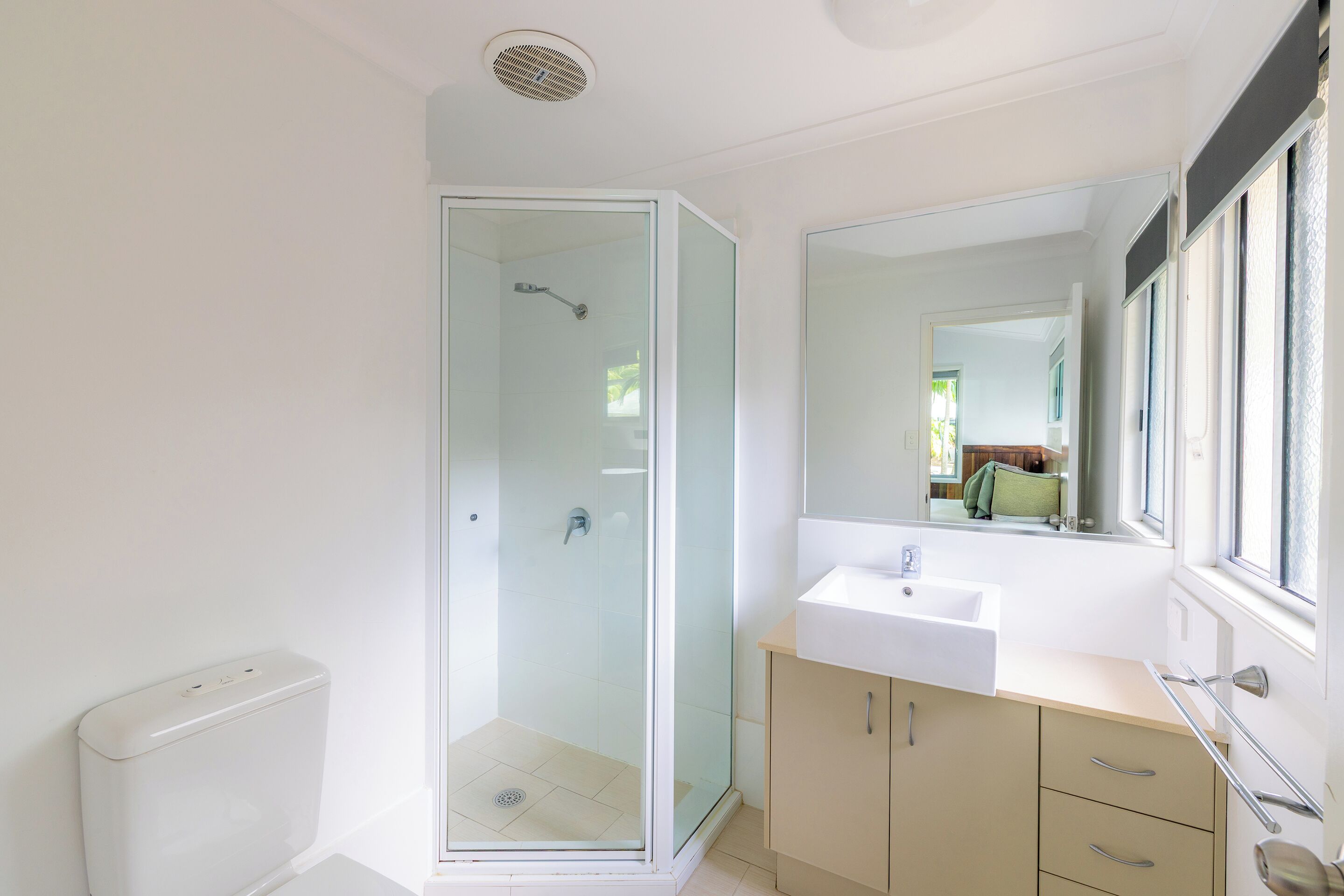 A bathroom with a glass-enclosed shower, a sink, and a mirror.