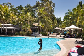 Relax by the resort pool surrounded by lush tropical vegetation and palm trees.
