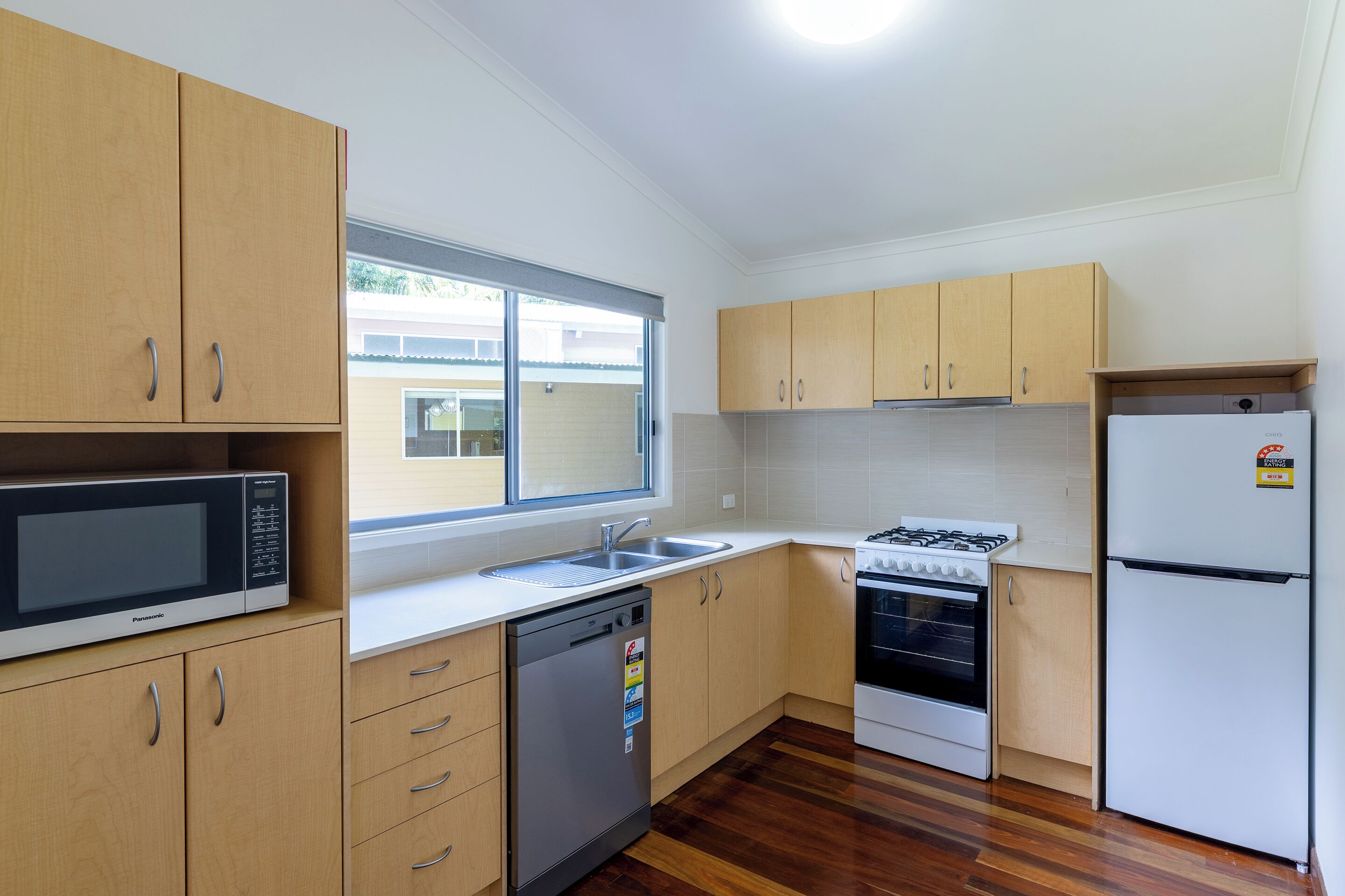 A kitchen with wooden cabinets, a dishwasher, a stove, a sink, and a refrigerator.