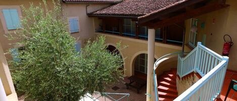 Un patio con una escalera, un árbol y un edificio de tejado a la vista.