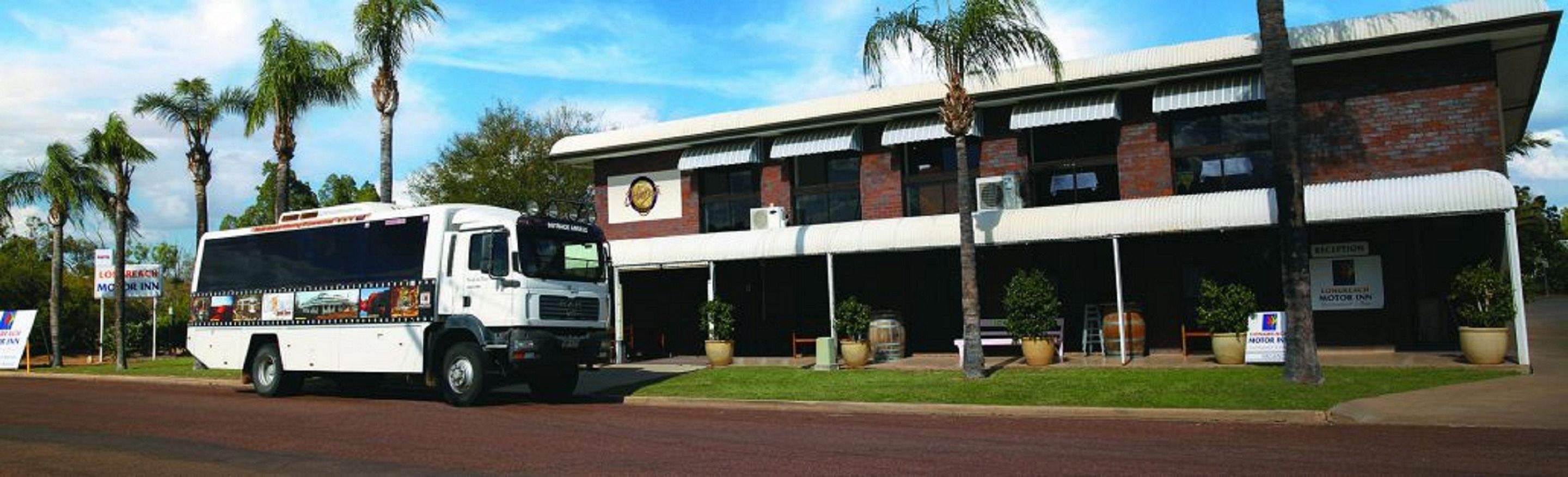 A white bus parked in front of a building with a reception area and a sign for 'Lostrechn Motor Inn'.