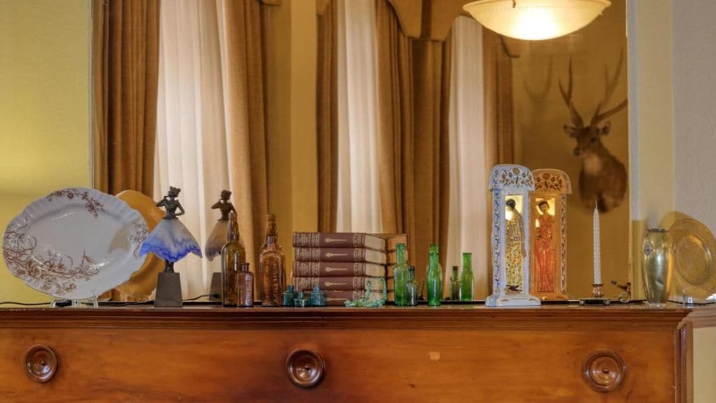 A wooden dresser with various decorative items including glass bottles, a plate, and figurines.