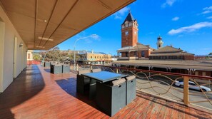 Un espace extérieur abrité, doté d’une terrasse en bois, de sièges et offrant une vue sur un clocher.