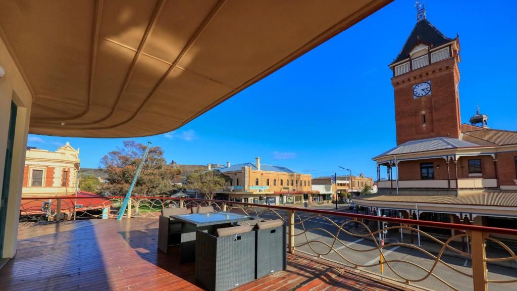 A balcony with a view of a town square, a clock tower, and buildings with distinct architectural styles.