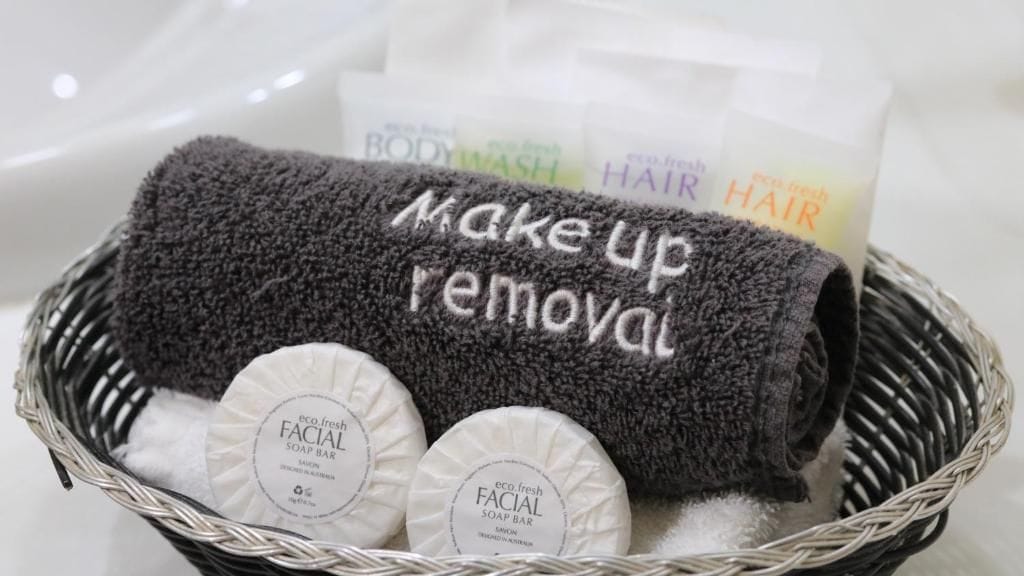 A basket containing a towel, two facial soap bars, and a body wash.