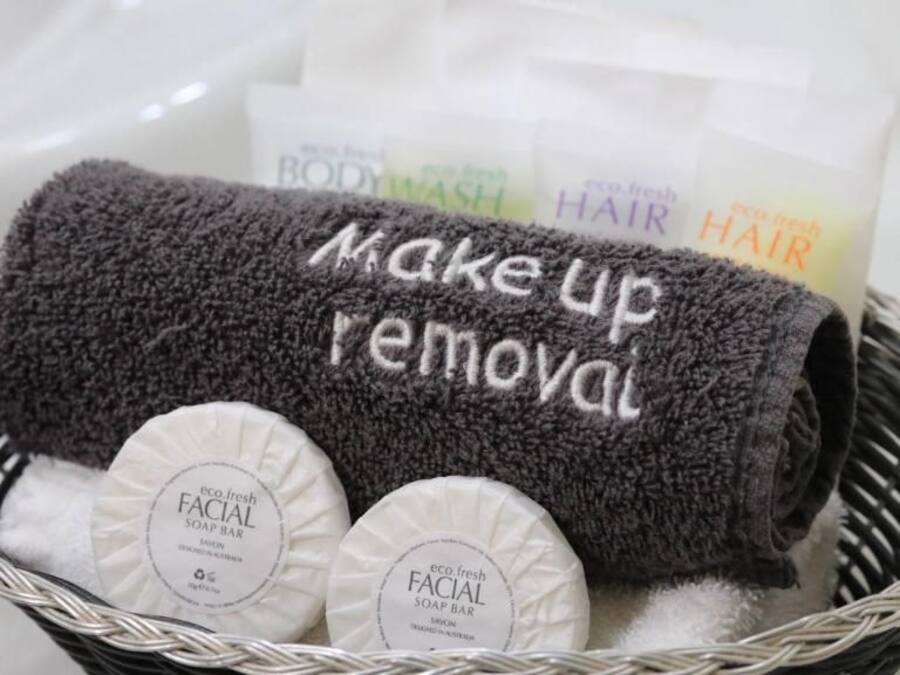 A basket containing a towel, two facial soap bars, and a body wash.