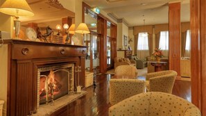 A traditional hotel lobby with a fireplace, comfortable seating, and a mirror reflecting the room. - Royal Exchange Hotel (Broken Hill)