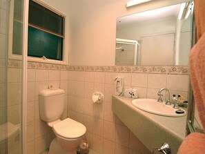 A bathroom with a toilet, sink, and mirror. - Wanderers Rest of Kangaroo Island (American River)