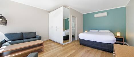 Un dormitorio moderno con cama, sofá, escritorio y armario.