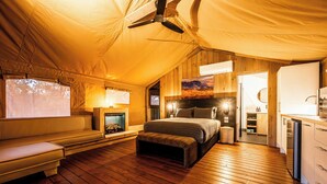 Una habitación con carpa, una cama, un banco y una kitchenette.
