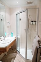 Un baño moderno con ducha envuelta en vidrio, tocador con lavabo y espejo.