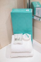 Un bagno con un lavandino bianco, uno specchio e una saponetta in una scatola color petrolio.