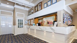 A reception area with a marble counter, framed certificates, and a wall-mounted information board. - European Hotel (Perth)