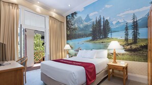 A hotel room with a large bed, two bedside tables, a desk, and a chair. There is a scenic mural on the wall depicting a mountain landscape and a lake. - European Hotel (Perth)