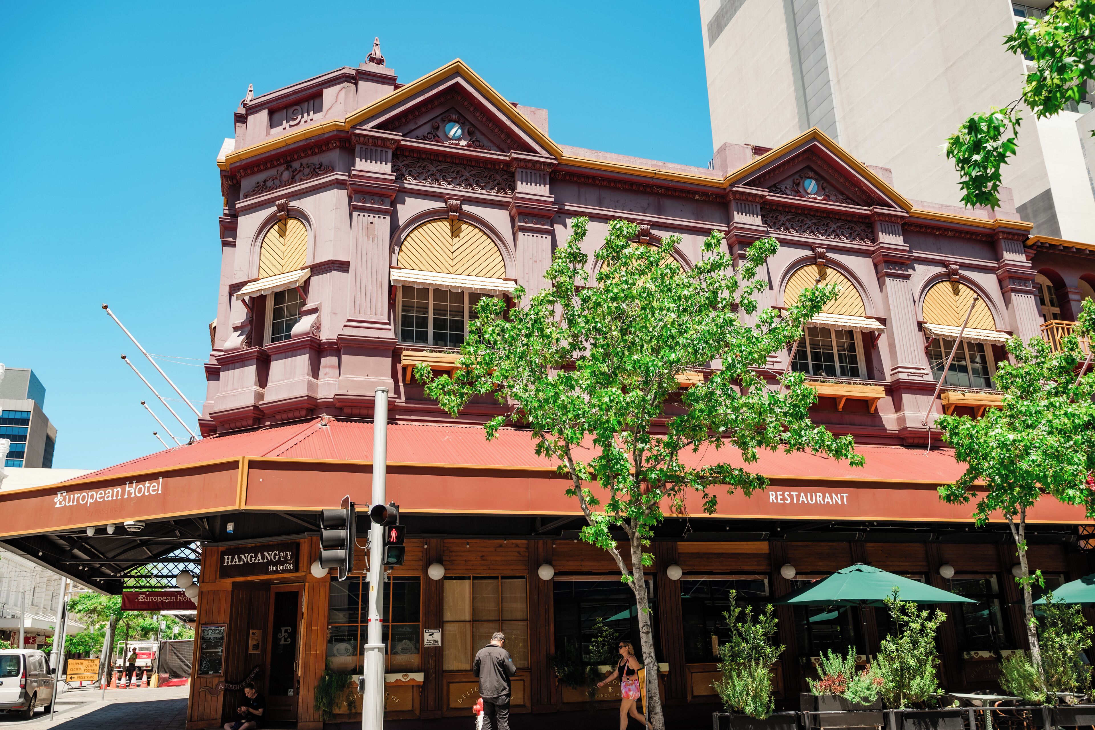 A European Hotel with a restaurant on the ground floor, featuring large arched windows and a red roof.