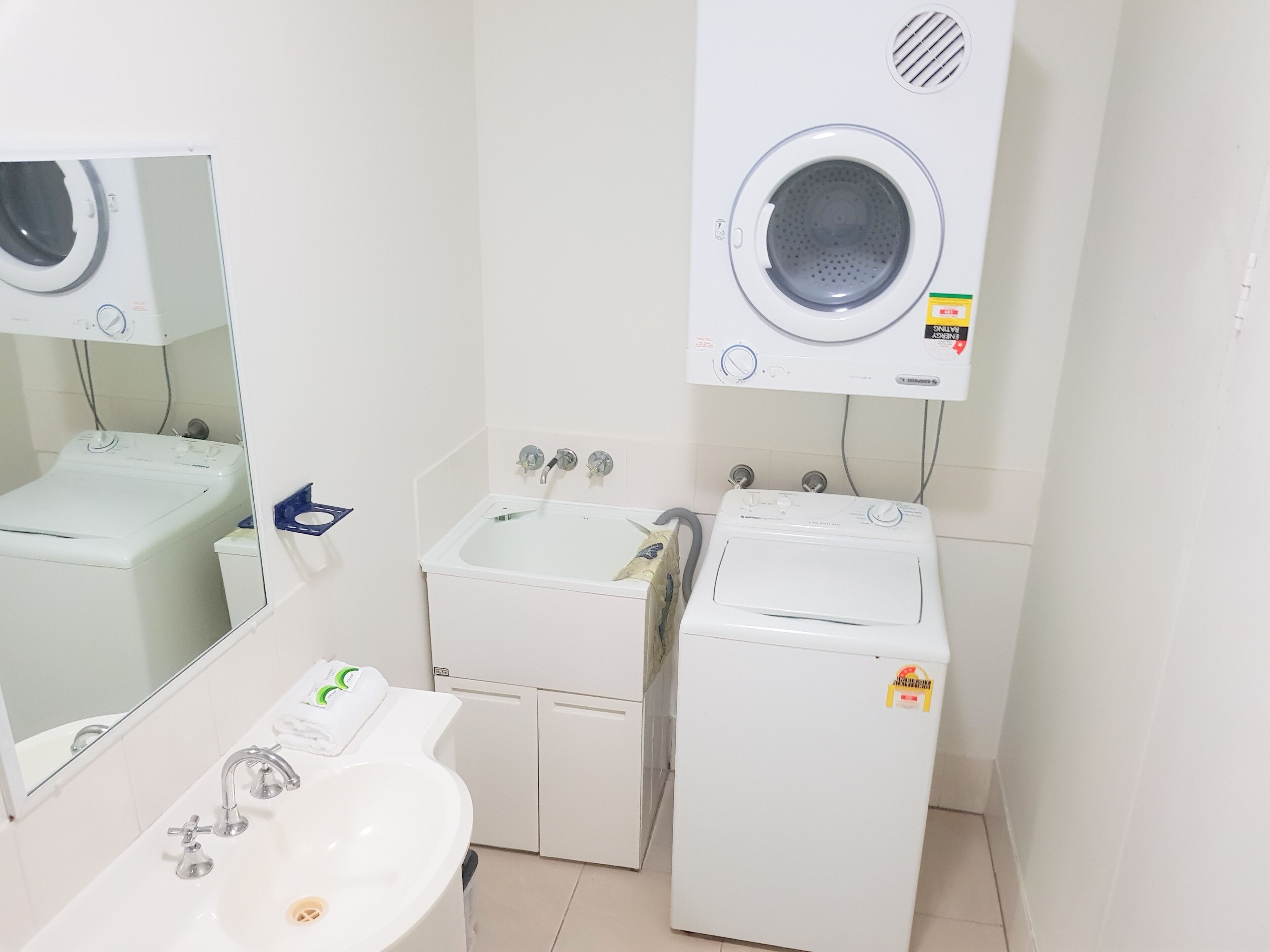 Una lavandería con lavadora, secadora y lavabo.