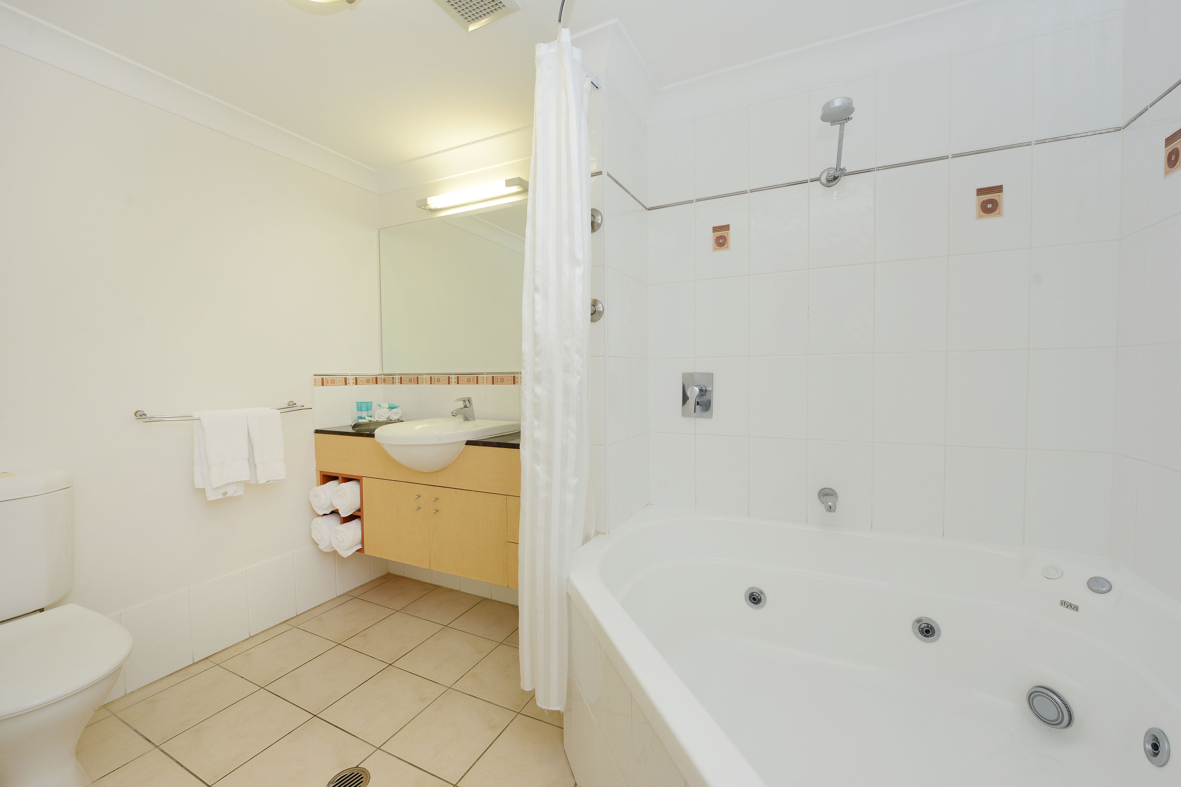 Een badkamer met toilet, wastafel, badkamermeubel en een groot bad.