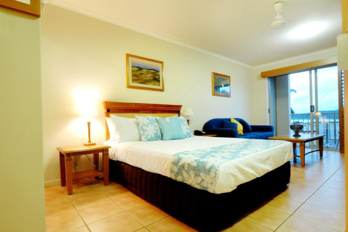 Une chambre d’hôtel avec un lit, une table de chevet, une lampe, un canapé et un balcon avec vue.