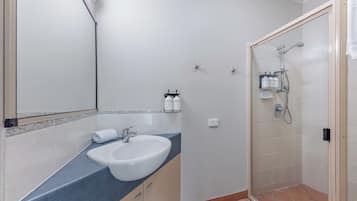A bathroom with a sink, mirror, and shower.
