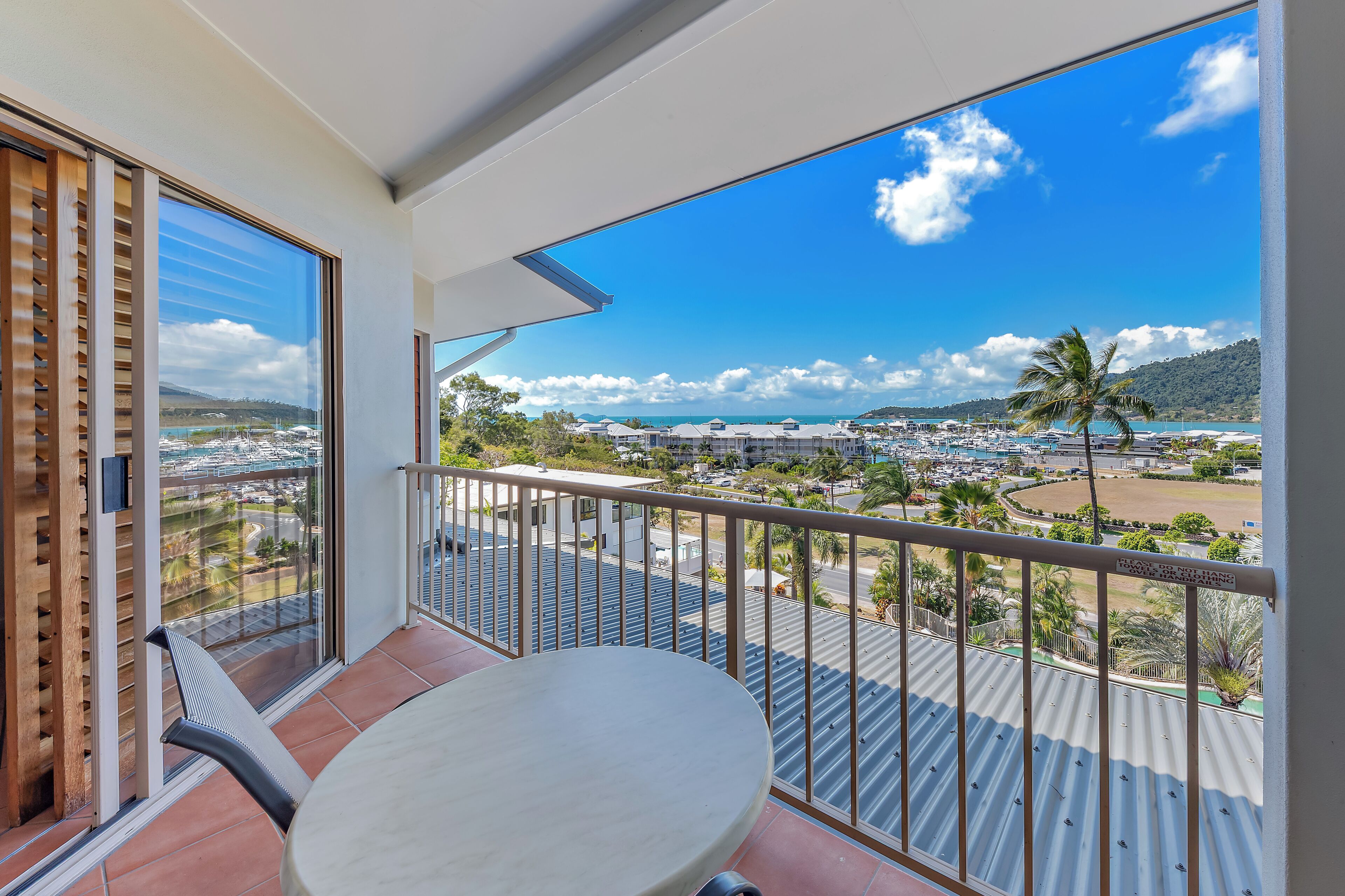 A balcony with a table and chairs, offering a view of a marina and buildings.