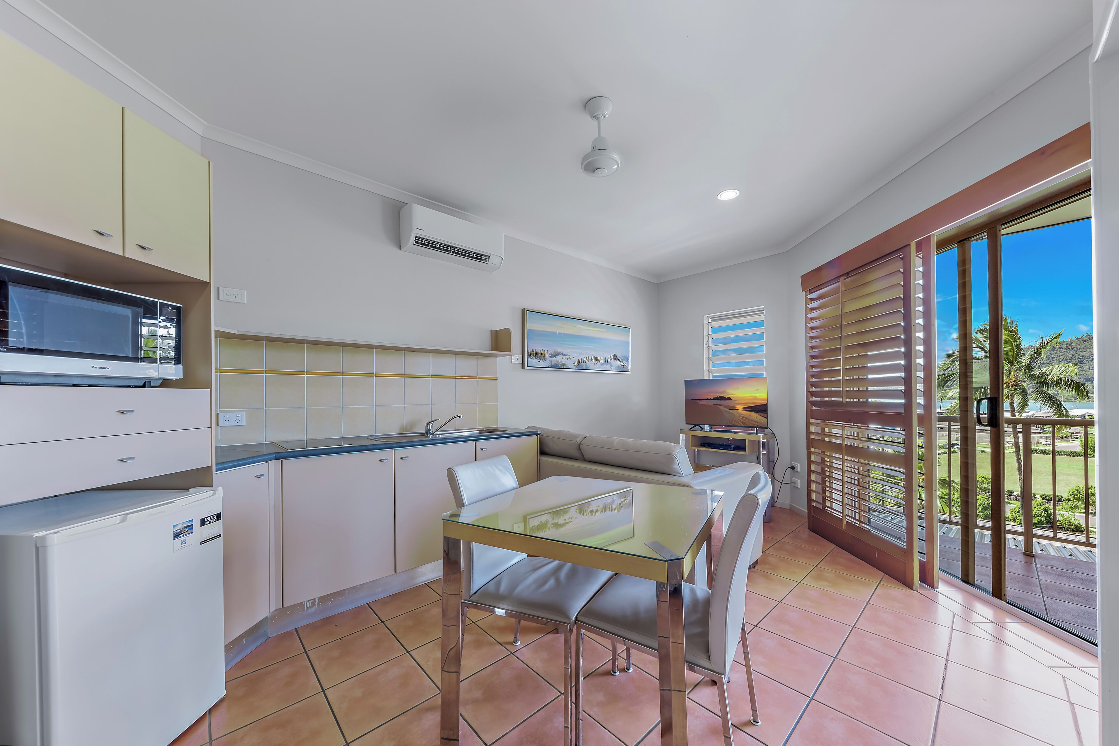 Une cuisine moderne avec un coin repas, un ventilateur de plafond et une vue sur l’extérieur.
