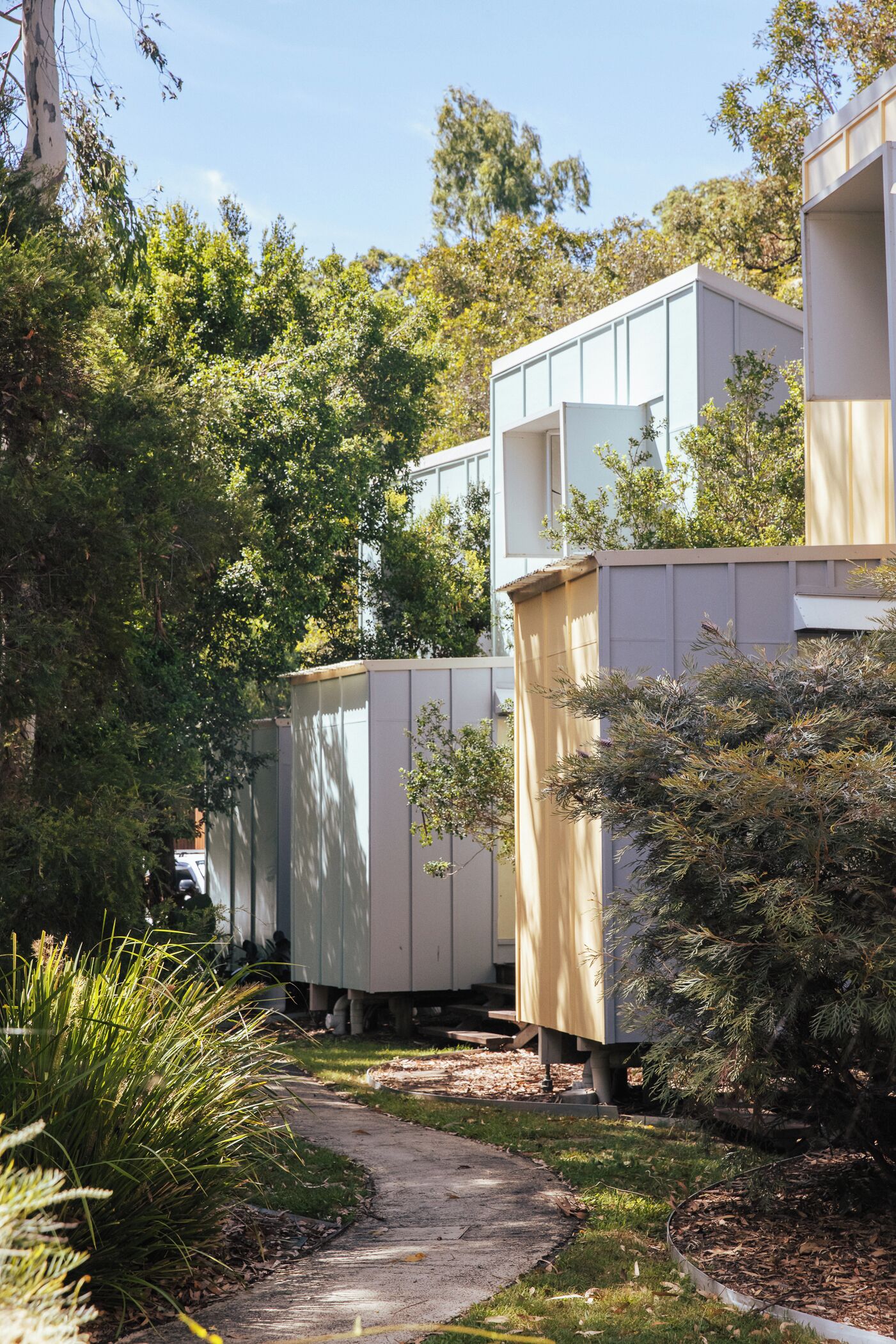 A pathway leading to a row of modern, white buildings with a covered outdoor area.