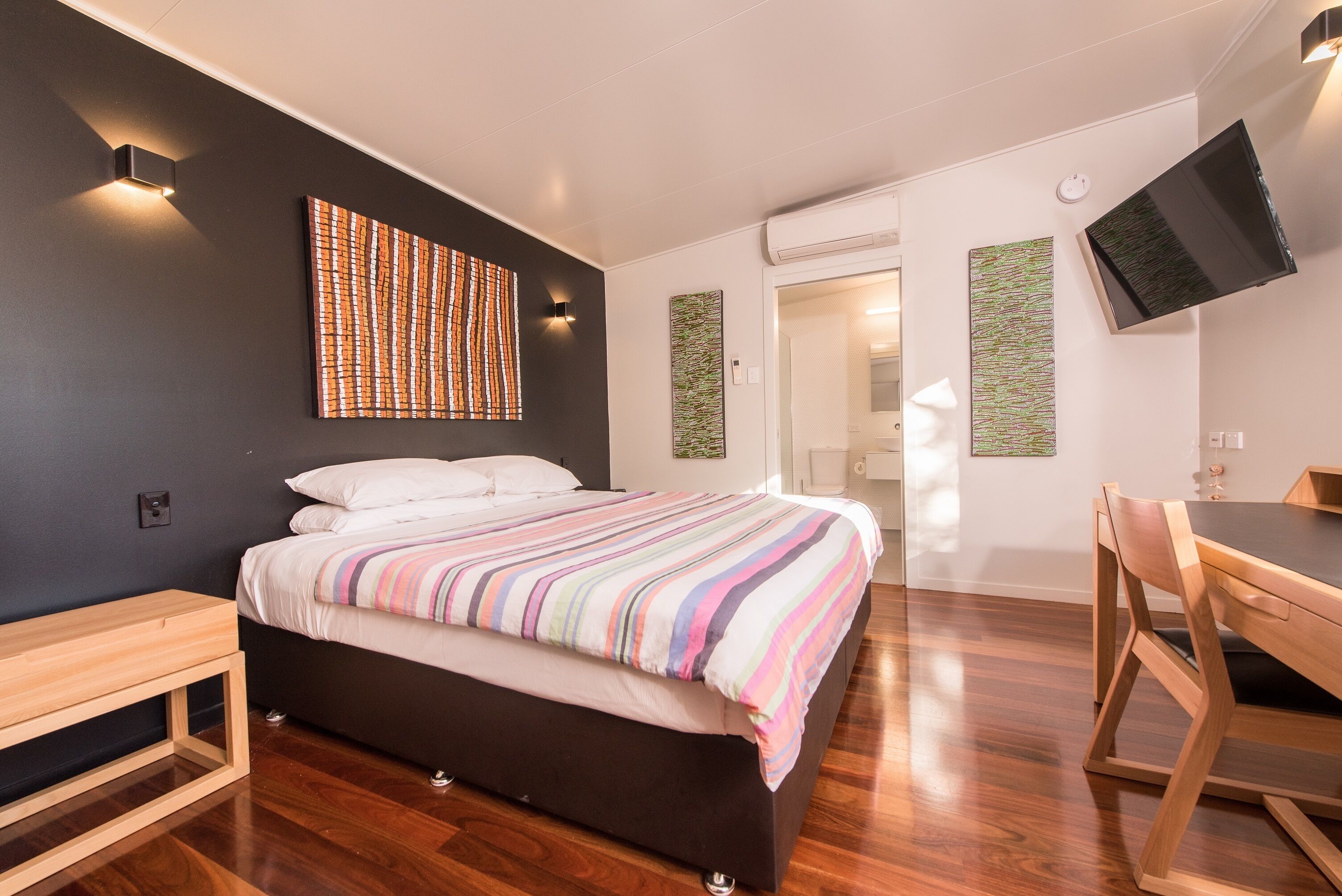 A modern bedroom with a bed, bedside table, and a desk with a chair.