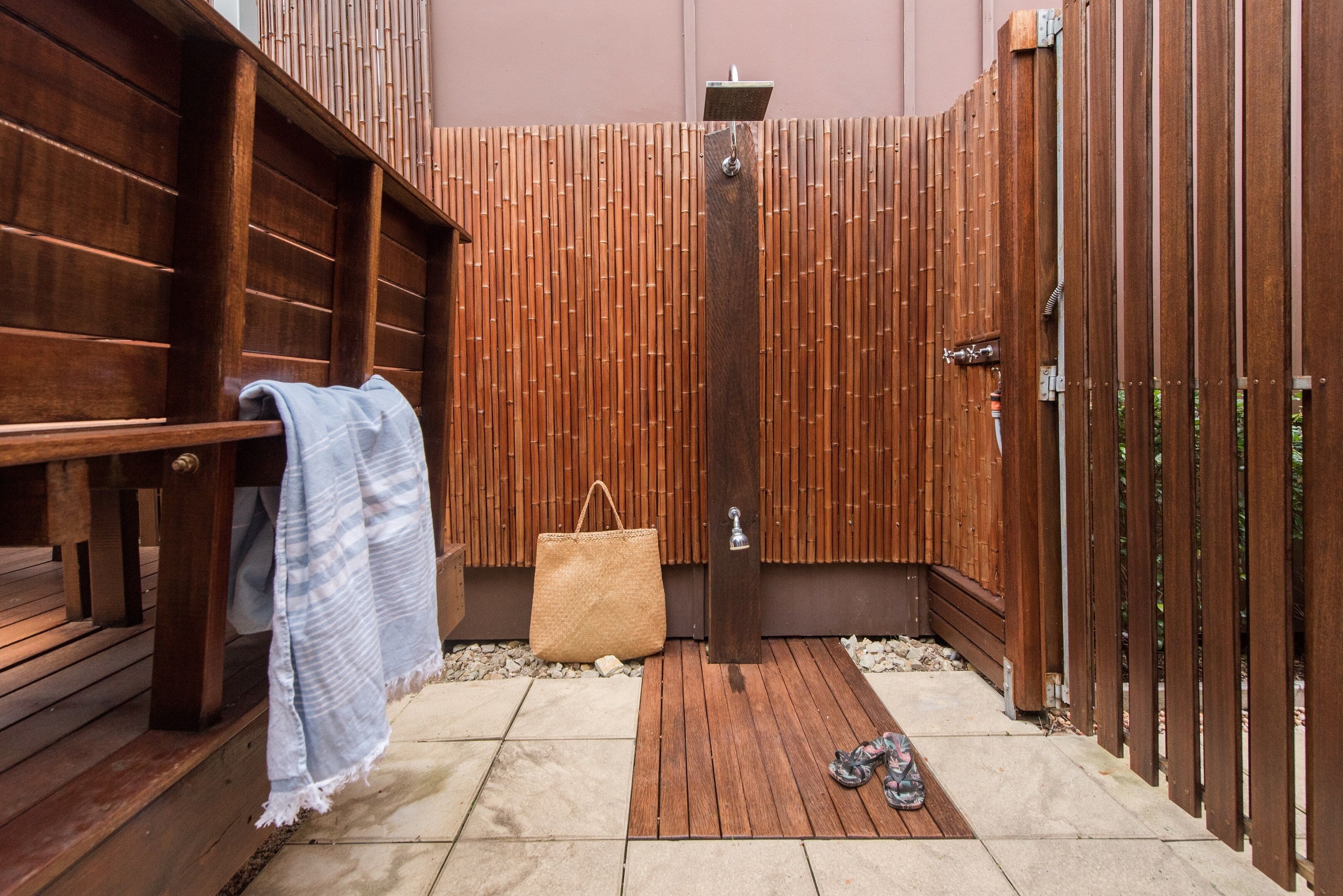 Une terrasse en bois avec un banc, une serviette et un sac en paille.